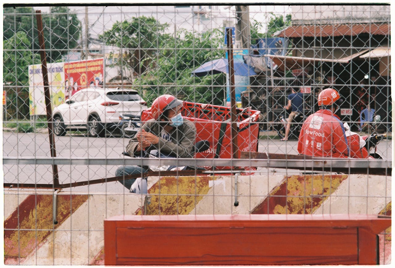 Food delivery riders on scooters taking a break in urban area.